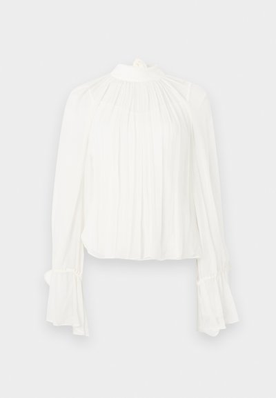 Valge pluus pikkade, lehvivate varrukate ja kõrge kaelusega. Ees pehmed voldid ja mansettidel kogumismotiiv.