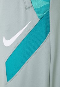 Hellgraue Sportshorts mit einem strukturierten türkisfarbenen Akzent und einem weißen Nike-Logo, gefertigt aus atmungsaktivem, dehnbarem Material.