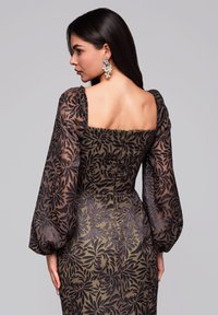 Kleid mit quadratischem Ausschnitt und durchsichtigen Puffärmeln, das ein florales Muster in Schwarz auf einem dunkelgrünen Hintergrund zeigt.