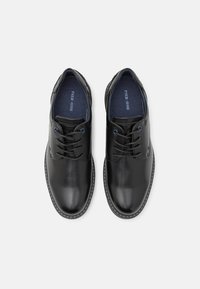 Chaussures noires en cuir avec une texture lisse, bout rond, semelle noire cousue, deux œillets et accents bleus à l'intérieur.