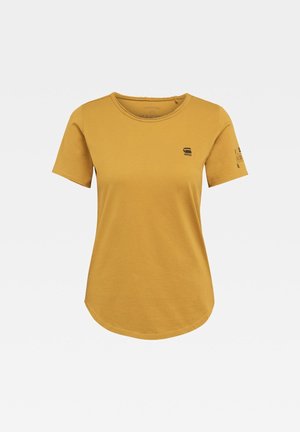 Musztardowożółty t-shirt z krótkim rękawem, okrągłym dekoltem, małym czarnym logo na lewej piersi i nadrukiem na prawym rękawie.