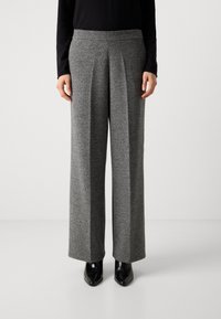 Wijdbeenbroek in een gestructureerde grijze stof, voorzien van voorplooien en een hoge tailleband. Gecombineerd met zwarte enkellaarsjes met hak.