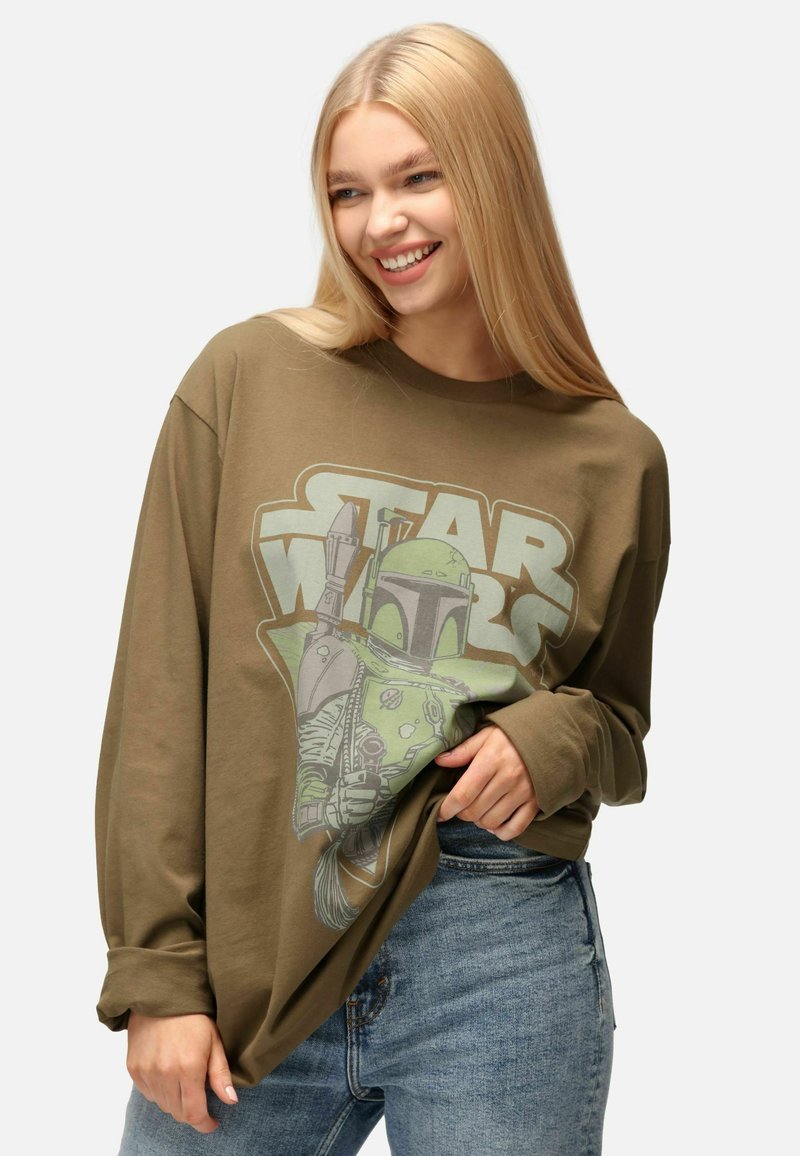 T-shirt a maniche lunghe verde oliva con stampa grafica di un personaggio e testo "STAR WARS" in bianco e verde. Design casual e dal taglio morbido.
