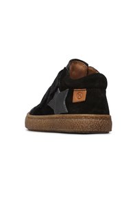 Baskets montantes en daim noir avec un accent en forme d'étoile noire, un patch de talon en cuir marron et une semelle en caoutchouc texturée.