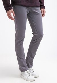 Šedé kalhoty z bavlněné směsi se slim fit, s hladkou texturou a jemnými švy, doplněné bílými teniskami.