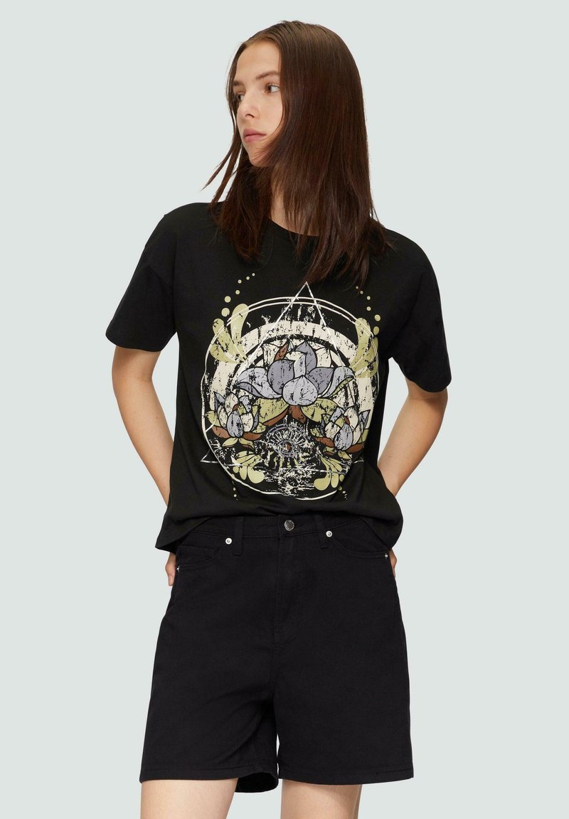 Schwarzes Baumwoll-T-Shirt mit einem grafischen Druck eines Baums mit Blumen, kombiniert mit schwarzen Shorts. Einfaches Design mit entspannter Passform.