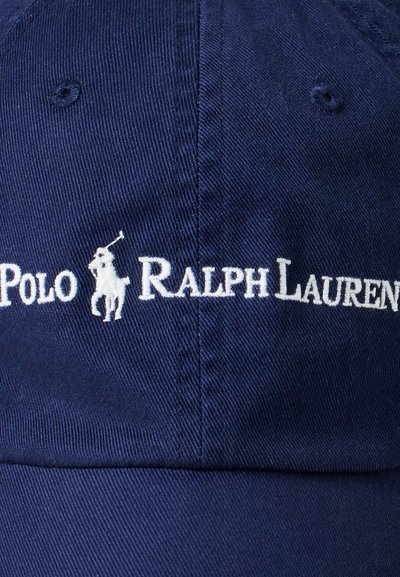 Jūras zila kokvilnas beisbola cepure ar baltu izšūtu zīmolu "Polo Ralph Lauren" un polo spēlētāja ikonu uz priekšējā paneļa.