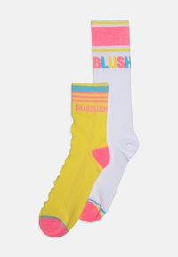Los calcetines tobilleros amarillos y blancos presentan rayas multicolores audaces y el texto "BILLIEBLUSH." El calcetín amarillo tiene acentos rosas en la punta.