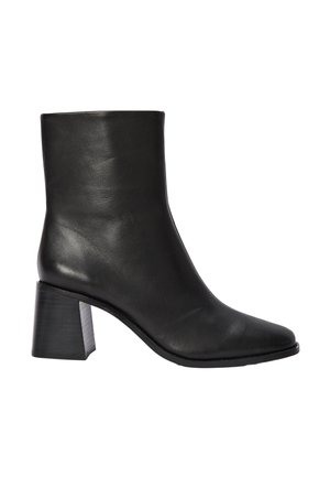 Bottine en cuir noir avec un bout pointu et un talon bloc. Texture lisse, design minimaliste et tige haute sans embellissements.