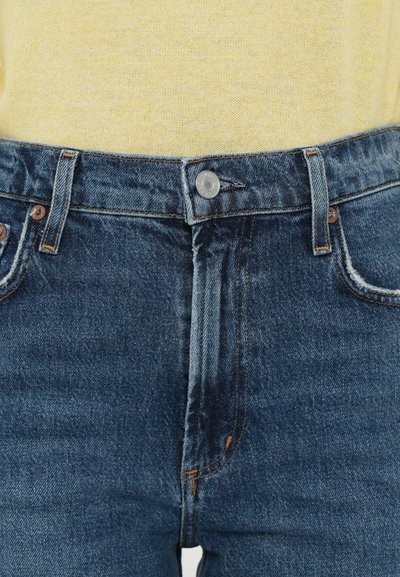 Išblukę mėlyni džinsai iš džinso audinio su aukštu liemeniu, metaliniu sagos užsegimu ir oranžinėmis siūlėmis. Faktūra: šiek tiek pažeista.