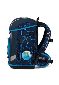 Dark blue backpack with a textured pattern in lighter blue, featuring multiple compartments, straps, and a circular dinosaur badge.