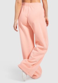Pantalones de chándal rosa claro con un corte relajado, que cuentan con una cinturilla elástica y piernas anchas, fabricados con un tejido suave para mayor comodidad.