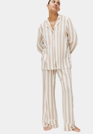 Beige-wit gestreepte pyjama van zachte stof, bestaande uit een overhemd met knopen en een zak, en losse broek met wijde manchetten.