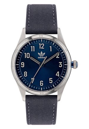 Montre analogique avec un cadran bleu foncé, des index argentés, un boîtier en acier inoxydable et un bracelet en tissu texturé gris foncé. Accent notoire de la couronne bleue.