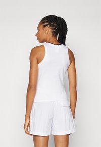 Witte mouwloze tanktop met een gladde textuur, die perfect aansluit bij lichte witte shorts. Heeft een ronde halslijn en een eenvoudig ontwerp.