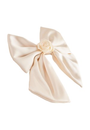 Cream-colored fabric bow with a central rose-shaped knot and two wide, flowing tails on a white background.