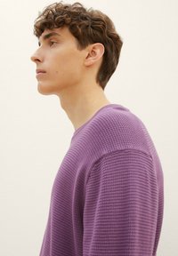 Maglione viola con texture e scollo rotondo, caratterizzato da un design a nido d'ape e dettagli a coste sulle maniche e sull'orlo.