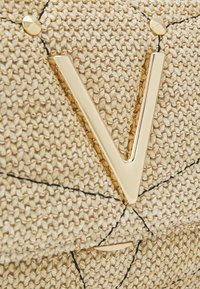 Torebka z plecionego słomy z błyszczącym złotym metalowym logo „V”, podkreślonym czarnym przeszyciem i złotym ćwiekiem dla dodatkowej faktury.