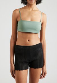 Groene bandeau top van soepel stof, gecombineerd met zwarte geribbelde shorts met een scalloped zoom. Eenvoudig ontwerp met verstelbare schouderbanden.