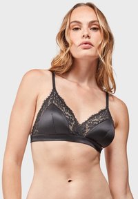 Bralette in tessuto nero con bordo in pizzo, coppe a forma di triangolo e spalline sottili e regolabili. Texture liscia con un dettaglio in pizzo a contrasto nella parte superiore.