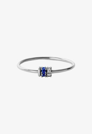 Anillo de plata que presenta tres acentos apilados: dos piedras azules y una piedra clara, colocadas sobre una banda lisa y delgada.