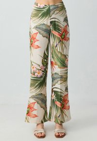 Pantaloni a palazzo con stampa tropicale in crema, caratterizzati da foglie verdi e fiori rosa e rossi. Realizzati in tessuto leggero con una finitura testurizzata.