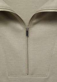 Lichtgroen ritsjack met een centrale rits en metalen hardware, gemaakt van een gladde, gestructureerde stof. Het ontwerp heeft een brede kraag.