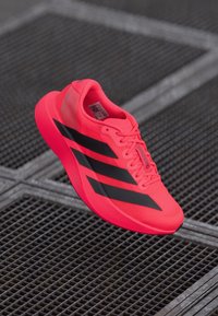 Lys pink sneakers med sorte striber, lavet af åndbart materiale, med et slankt design og tekstureret sål for godt greb.