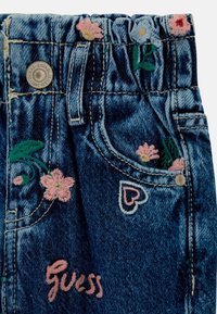 Pantaloni corti in denim con vita elastica, caratterizzati da ricami floreali rosa e verdi e un design a forma di cuore. "Guess" ricamato in rosa.