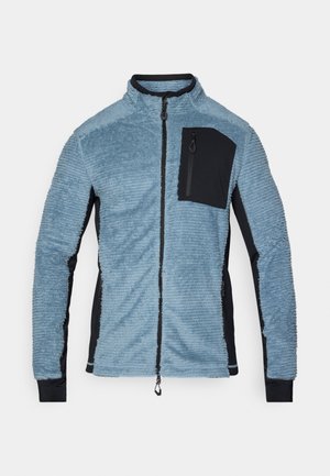 Giacca in pile di colore azzurro chiaro con accenti neri. Presenta una zip frontale, un colletto alto e una tasca sul petto con zip. Tessuto morbido e testurizzato.