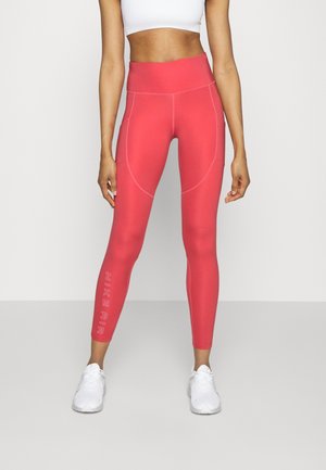 Leggings ajustés taille haute de couleur rose vif avec des coutures contrastées et l'inscription "NIKE AIR" imprimée sur la jambe inférieure, fabriqués en tissu extensible.