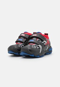 Scarpe per bambini nere e rosse con doppie fasce in Velcro, caratterizzate da un design di ragnatela, dettagli blu e una suola in gomma testurizzata.