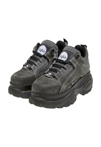 Pár šedých chunky platform tenisky značky Buffalo s čiernymi šnúrkami a hrubými, štruktúrovanými čiernymi podrážkami.