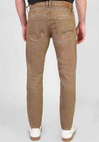 Lichtbruine denim jeans met subtiele textuur, slim fit, achterzakken met lichte stiksels en een leren label op de tailleband.