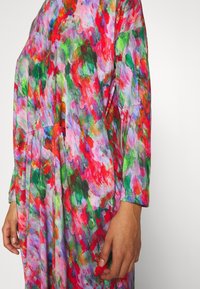 Langärmliges, lebhaftes Kleid mit einem bunten abstrakten Muster in Pink, Rot, Grün und Lila, das eine lockere Passform und weichen Stoff aufweist.