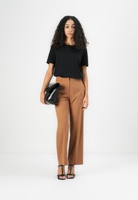 Mustapaita, jossa lyhyet hihat, yhdistetty korkeavyötäröisiin kamelinvärisiin leveälahkeisiin housuihin. Asusteina musta clutch-laukku ja remmilliset mustat korkokengät.