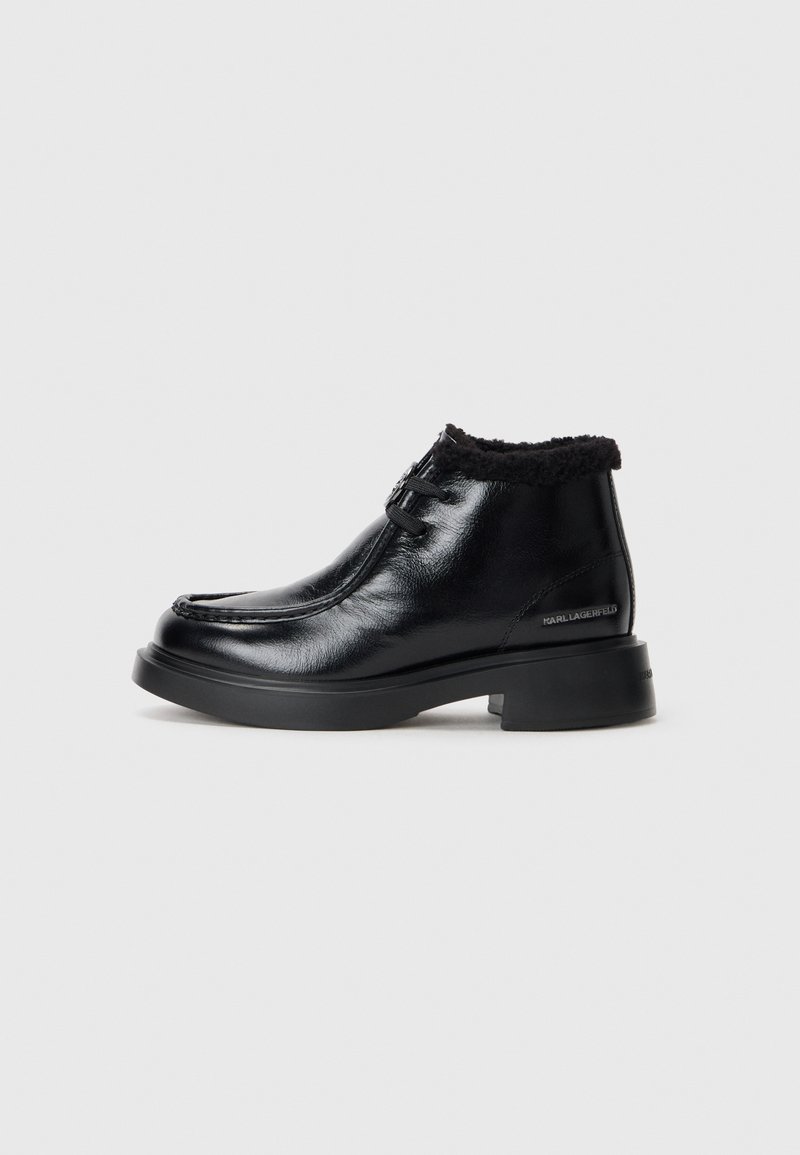 Bottines en cuir noir avec une finition brillante, doublure en fourrure autour du col, design à bout rond et semelle en caoutchouc noire épaisse.