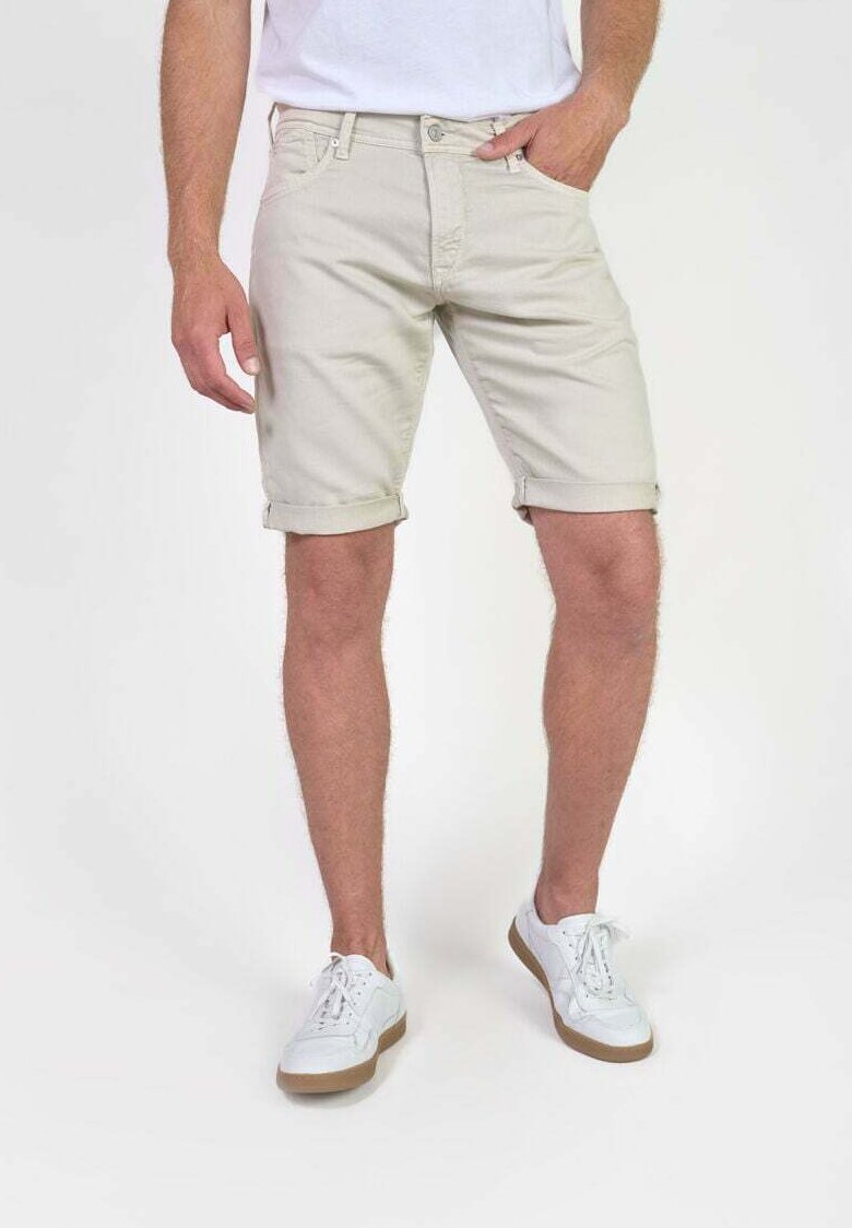 Shorts en coton beige avec des ourlets roulés, poches avant et une coupe classique, associés à des baskets blanches avec semelles en caoutchouc et un design à lacets.
