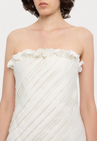 Strapless jurk vervaardigd uit witte stof, met gerimpelde accenten bij de halslijn en verticale plooien door het hele lijf.