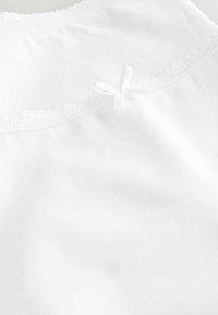 Witte blouse met een ronde halslijn, voorzien van delicate kantafwerking en een kleine witte strik accent in het midden achter.