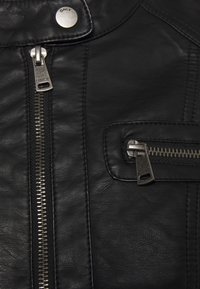Černá kožená bunda s předním zipem, zipovou kapsou na hrudi a kovovými doplňky. Materiál má texturovaný povrch.