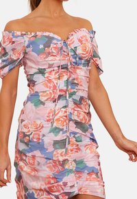 Blommig off-shoulder klänning i rosa, med volangärmar, rynkad textur och dragsko-detajl vid bysten.