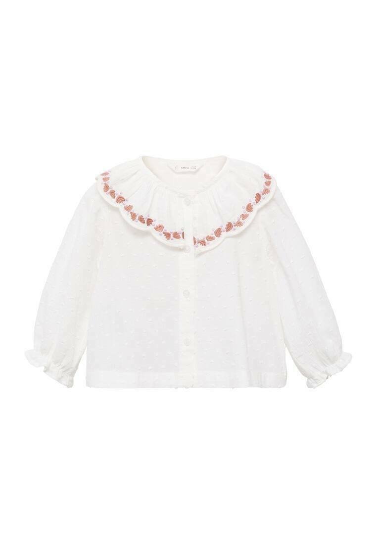 Bluză albă cu guler volă, decorată cu broderie florală roz. Mâneci lungi cu manșete elastice și textură punctată pe toată suprafața.