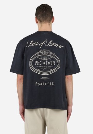 Zwarte oversized t-shirt met witte bedrukte tekst en afbeeldingen op de achterkant, waaronder "Scent of Summer" en "Pegador Club."