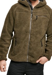 Giacca in fleece verde oliva con superficie testurizzata, chiusura con zip davanti, cappuccio regolabile e due tasche anteriori con zip. Presenta una tasca sul petto con zip.