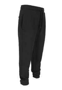 Zwarte joggingbroeken gemaakt van katoenen stof met een elastische tailleband, verstelbare trekkoord, zijzakken en smalle boorden bij de enkels.