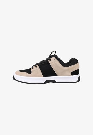 Beige a čierne atletické topánky vyrobené z semišu a sieťoviny s bielou gumovou podrážkou, s šnurovaním vpredu a polstrovaným golierom.