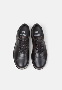 Svarta sneakers i läder med släta och texturerade ytor. Utrustade med snörningssystem och logoinlägg. Klassisk design med subtila mönster.