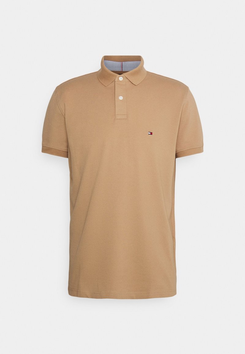 Polo beige à manches courtes avec deux boutons blancs, col et petit logo rectangulaire sur le côté gauche de la poitrine.