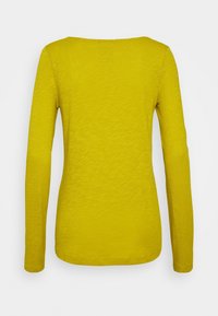 Maglia donna a maniche lunghe di colore giallo senape con scollatura a barca, vista da dietro su sfondo bianco.